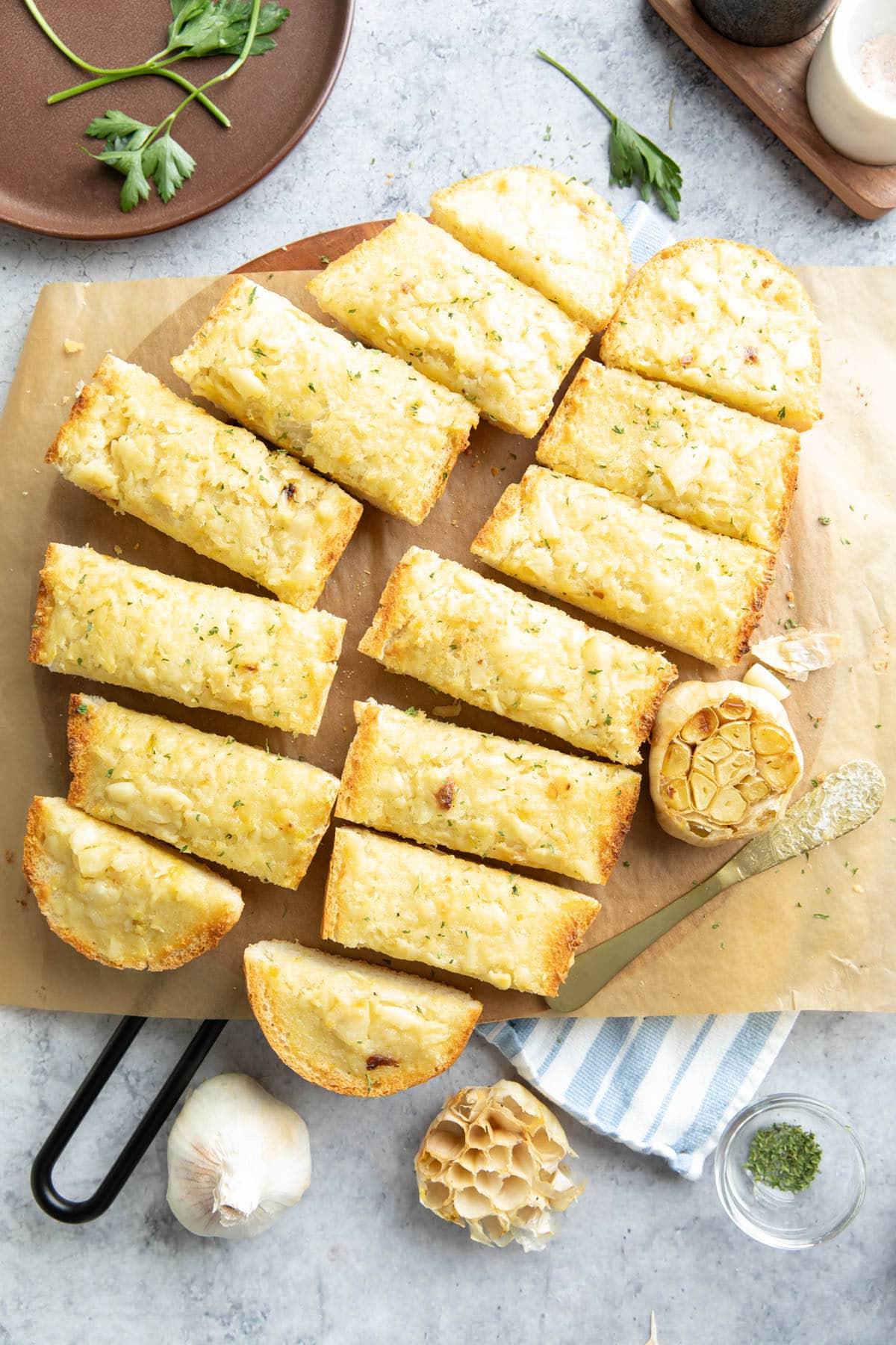 Geröstetes Knoblauchbrot {Hausgemachtes Rezept} 2 Geschnittenes geröstetes Knoblauchbrot auf einem hölzernen Servierbrett