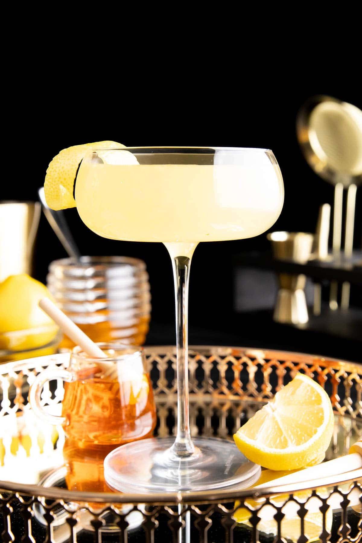 Bienenkniee-Cocktail 2 Ein Bee’s Knees Cocktail in einem Glas mit Zitronengarnitur