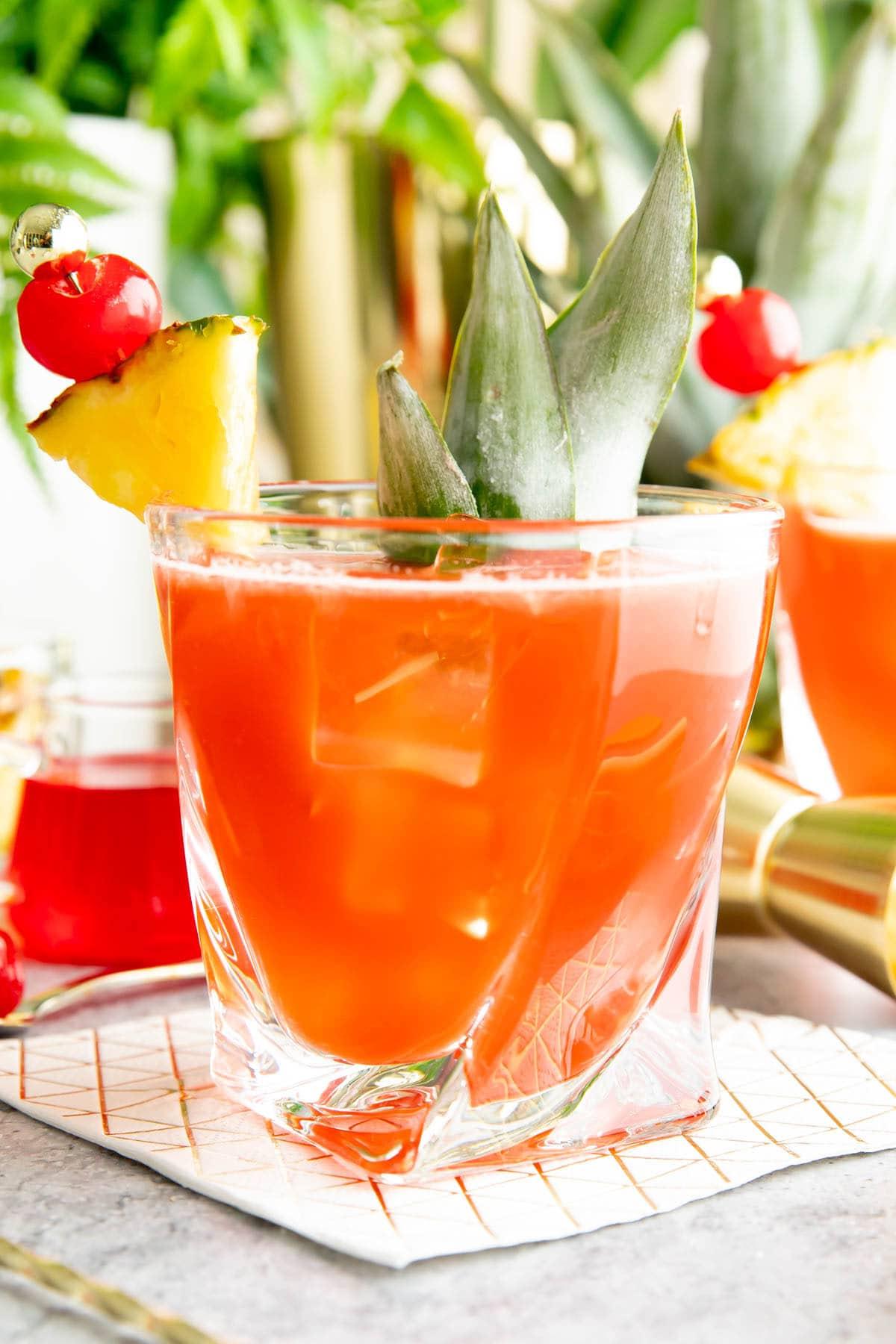 Dschungelvogel Cocktail 2 Ein nahaufnahme des Jungle Bird Cocktails, garniert mit einer Ananasspalte und einer Kirsche