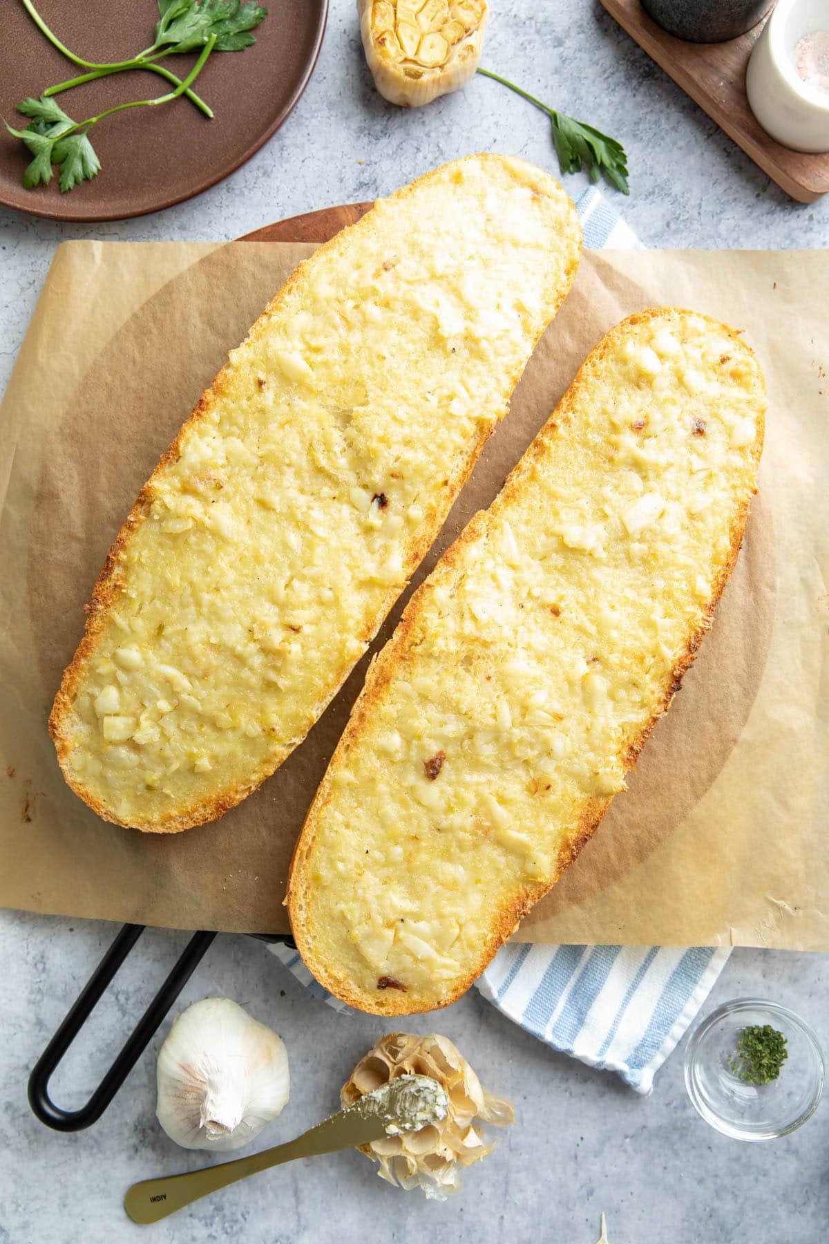 Geröstetes Knoblauchbrot {Hausgemachtes Rezept} 11 Vollständig gebackene Brothälften mit Aufstrich auf einem Servierbrett