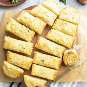Geröstetes Knoblauchbrot {Hausgemachtes Rezept} 14 Scheiben geröstetes Knoblauchbrot auf einem mit Backpapier belegten Servierbrett