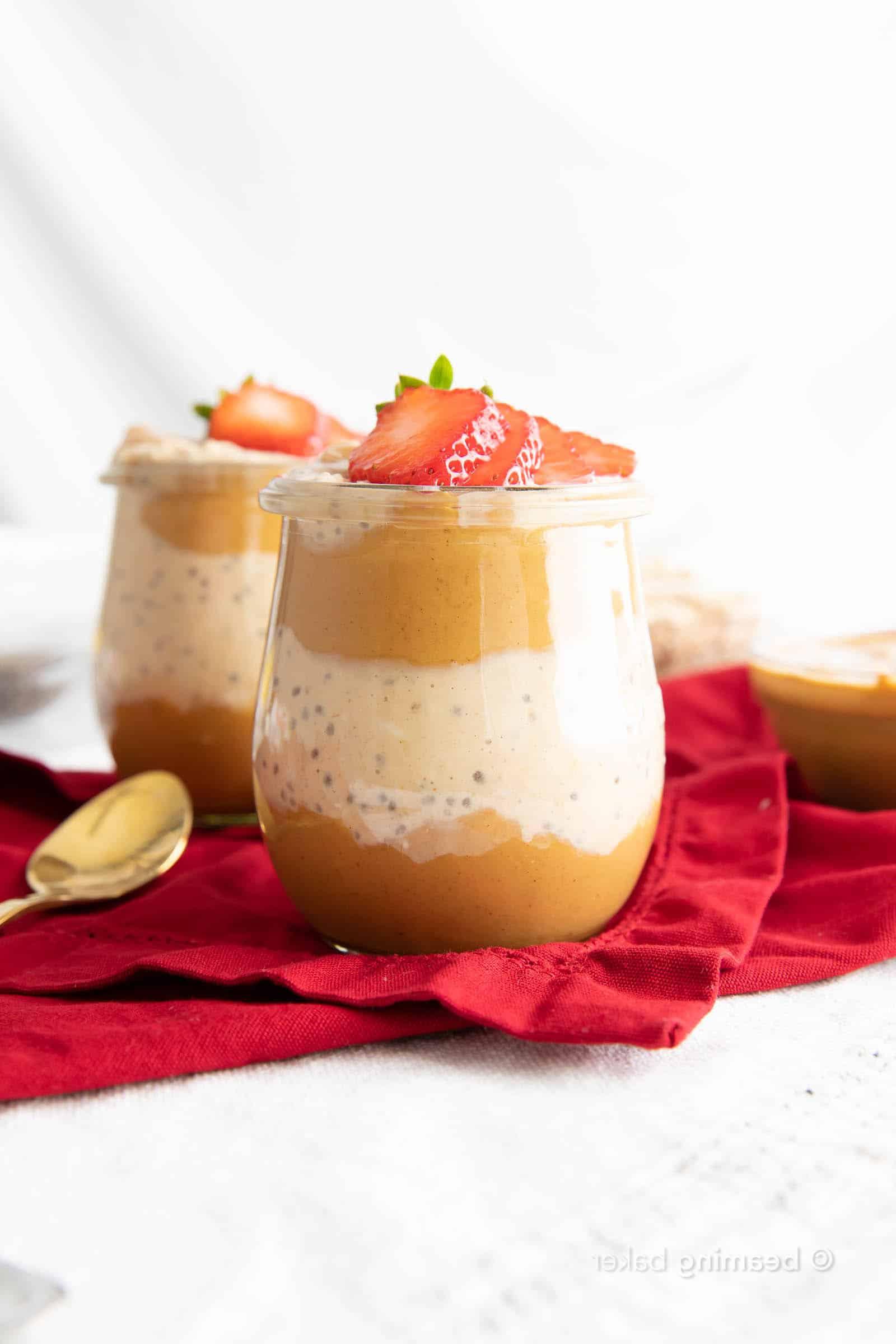 Zwei Gläser Erdnussbutter Overnight Oats mit einem goldenen Löffel