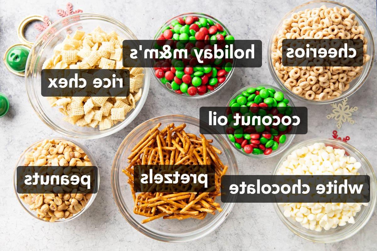 Weihnachts-Puppy Chow 3 Schüsseln mit Brezeln, Reis-Chex, Cheerios, Erdnüssen, roten und grünen Weihnachts-M&M-Bonbons und weißen Schokoladenstückchen zur Herstellung von Weihnachtlichem Rentierfutter