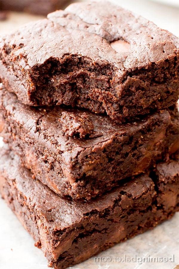 Vegane glutenfreie Brownies 3 Ein angebissener veganer GF-Brownie liegt auf zwei weiteren Brownies auf Wachspapier