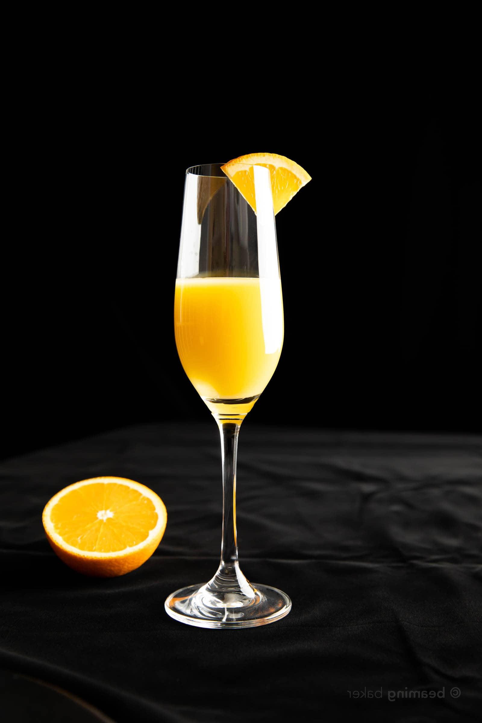 Ein halb gefülltes Glas frischer Orangensaft, garniert mit einem Orangenkeil