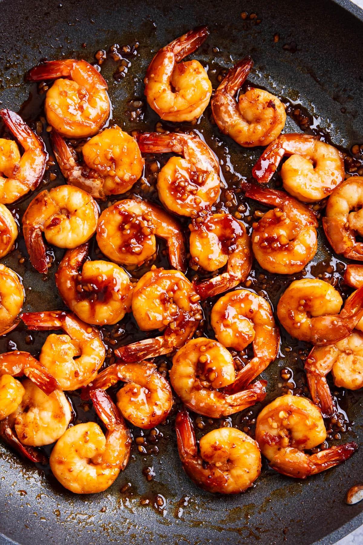 Gegarte asiatische Knoblauchgarnelen in einer Pfanne, gefüllt mit aromatischer, besser als vom Imbiss schmeckender Sauce.