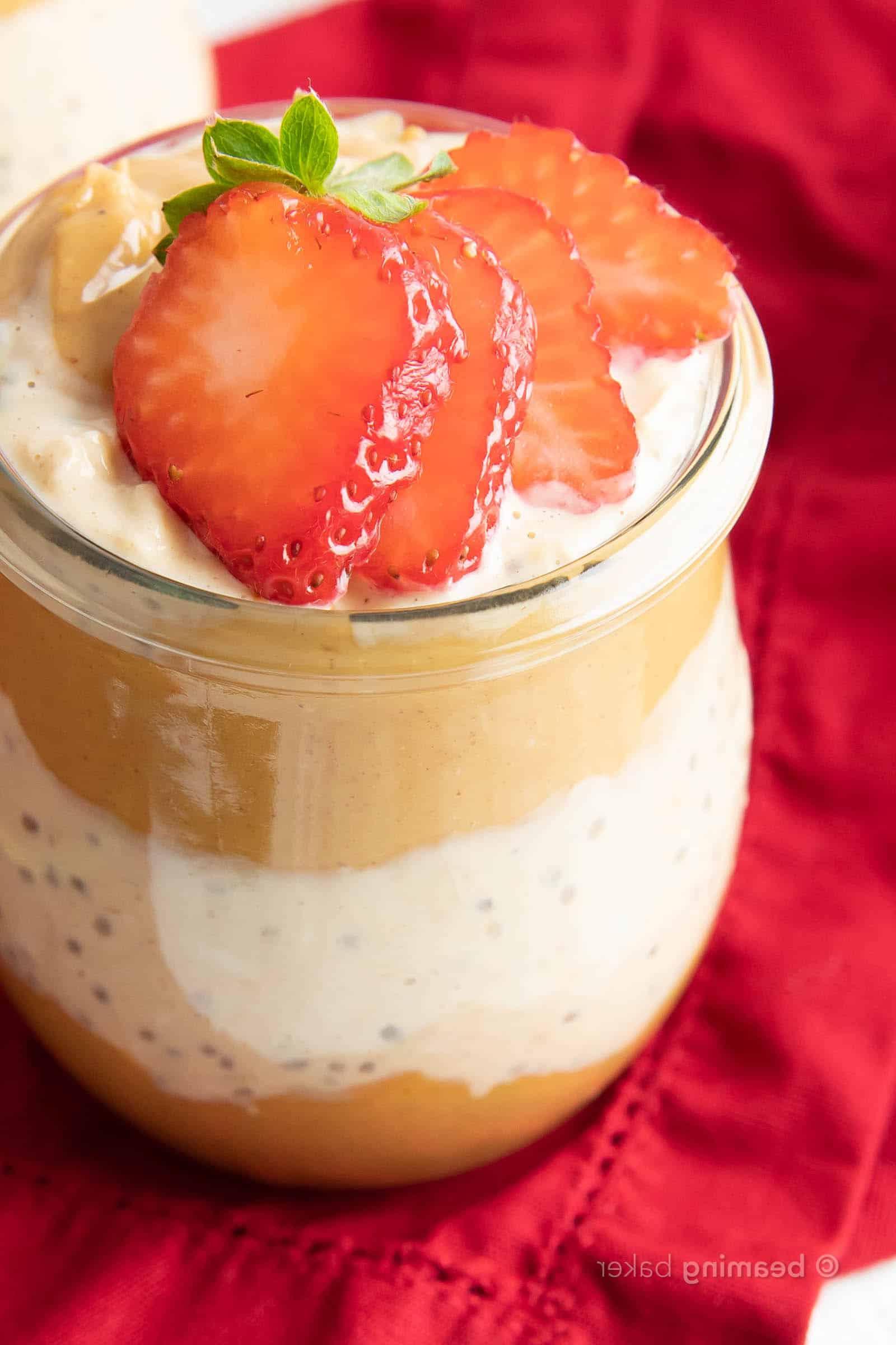 Frische, geschnittene Erdbeeren auf Schichten von Erdnussbutter und Overnight Oats mit Erdnussbutter