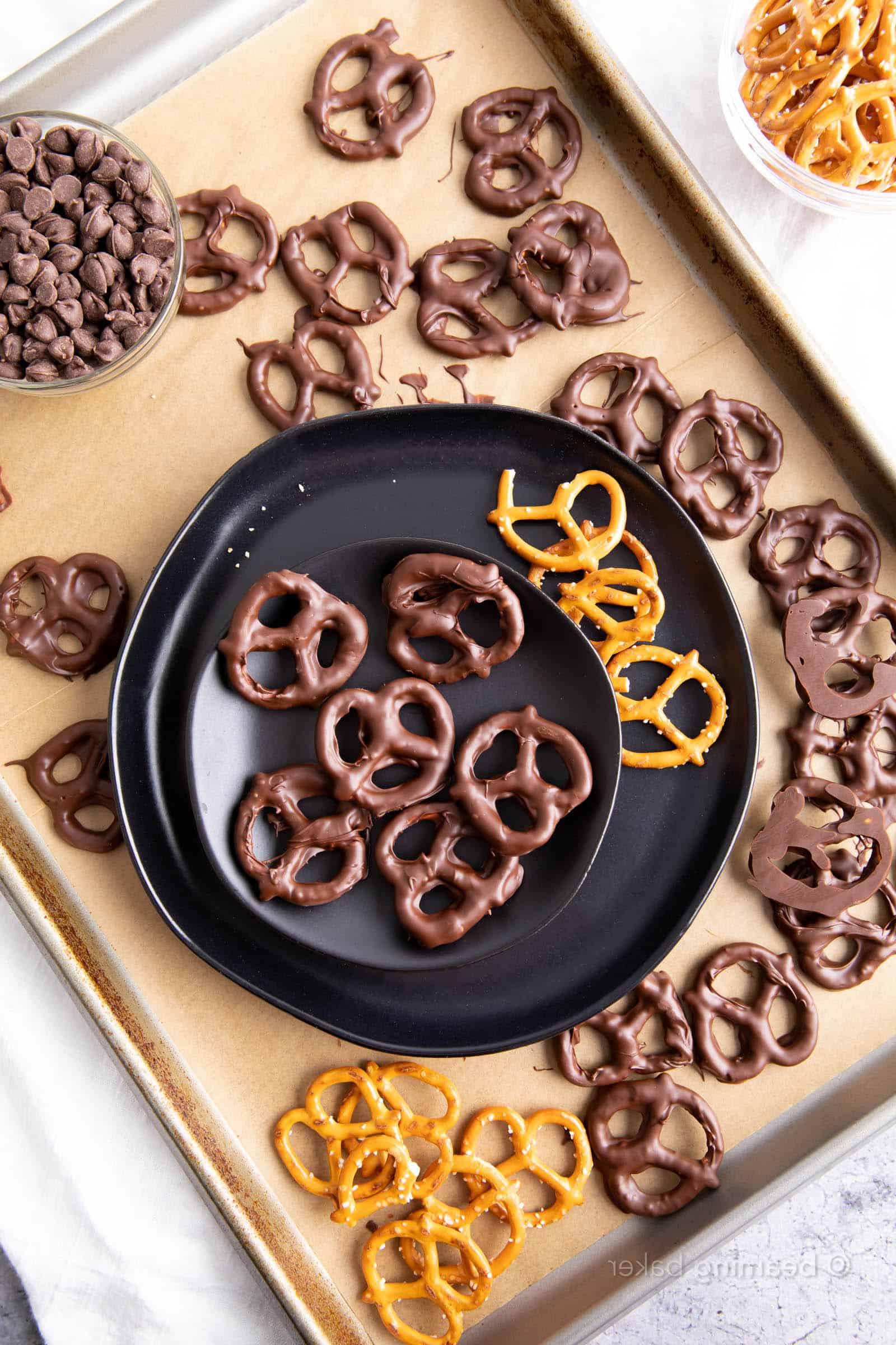 Appetitlich angerichtete vegane Schoko Brezeln auf einem Teller, umgeben von weiteren schokolierten und normalen Brezeln