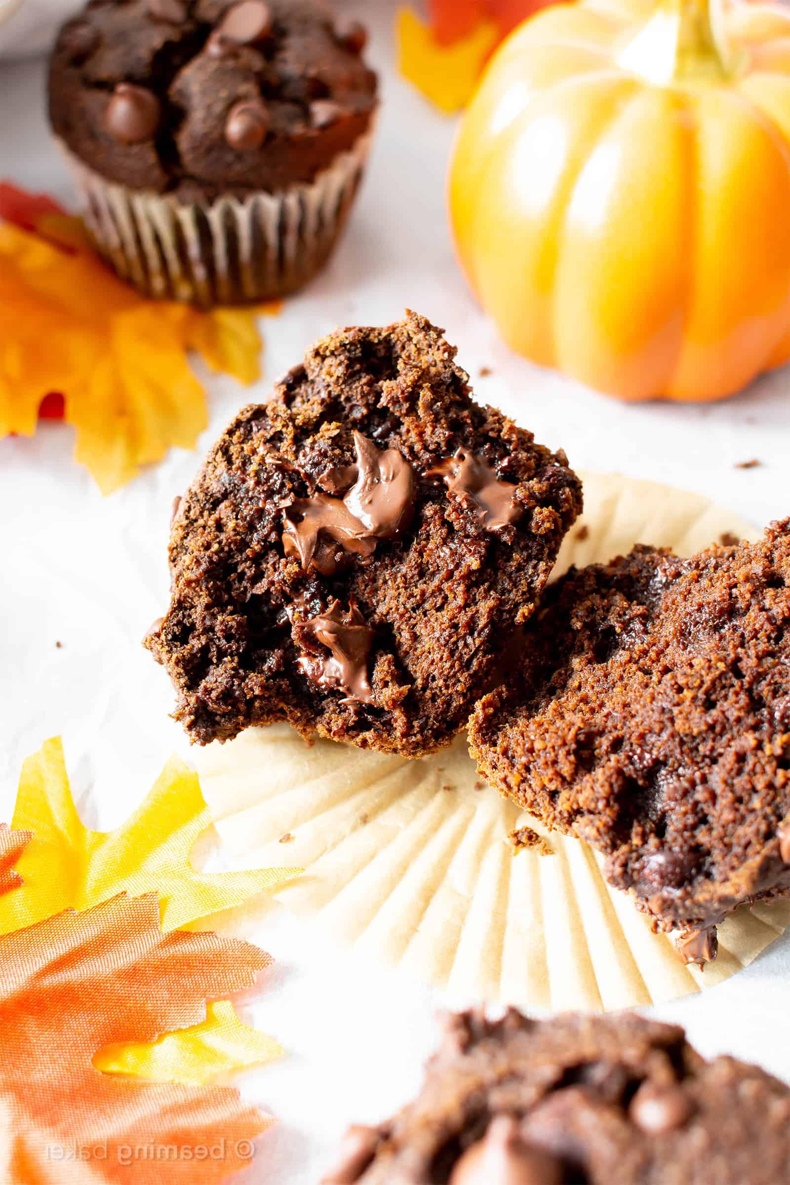 Gabel teilt einen frisch gebackenen glutenfreien veganen Schoko-Kürbis-Muffin, der die saftige Textur und die Schokoladenstücke enthüllt.