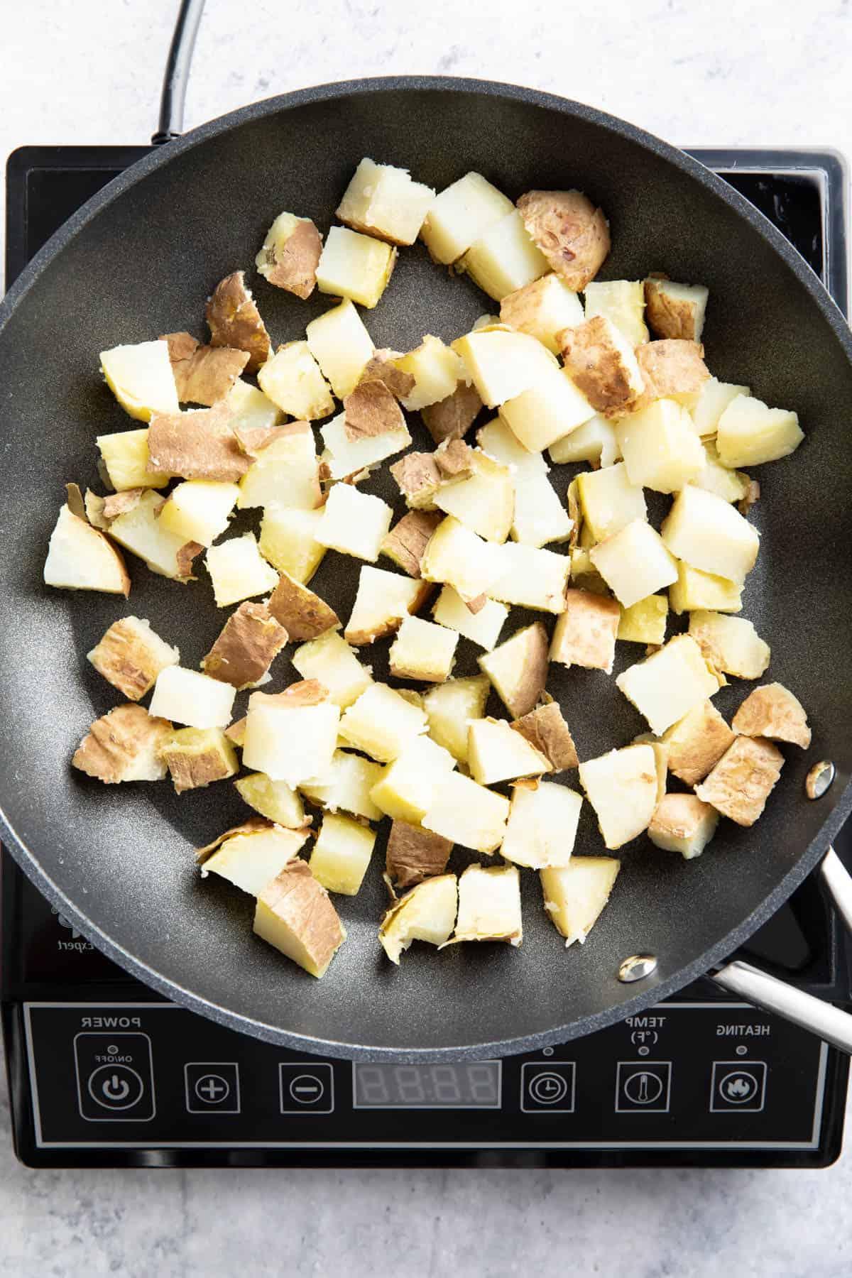 **So werden Frühstückskartoffeln knusprig!** 5 Gehackte Kartoffeln kochen in einer antihaftbeschichteten Pfanne über der Hitze