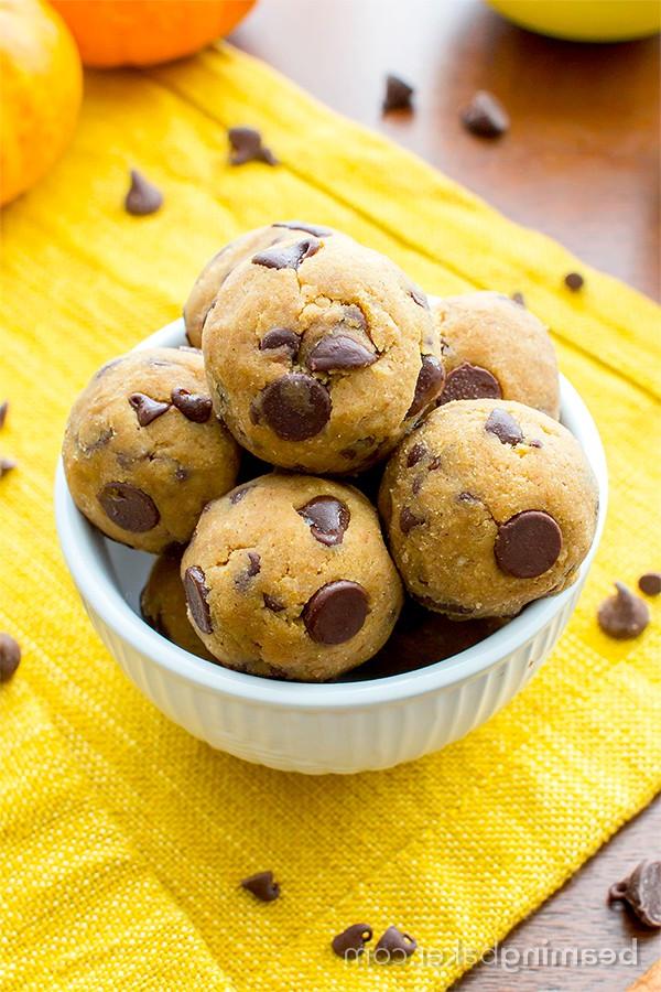 **Ungebackene Kürbis-Schokostückchen-Keksteig-Kugeln (Paleo, Vegan, Glutenfrei, Milchfrei)** 5 Hand hält ein einzelnes Kürbis-Schoko-Keksteig-Häppchen, betont die weiche Textur und die Schokostückchen. Ein gesunder Genuss für unterwegs.