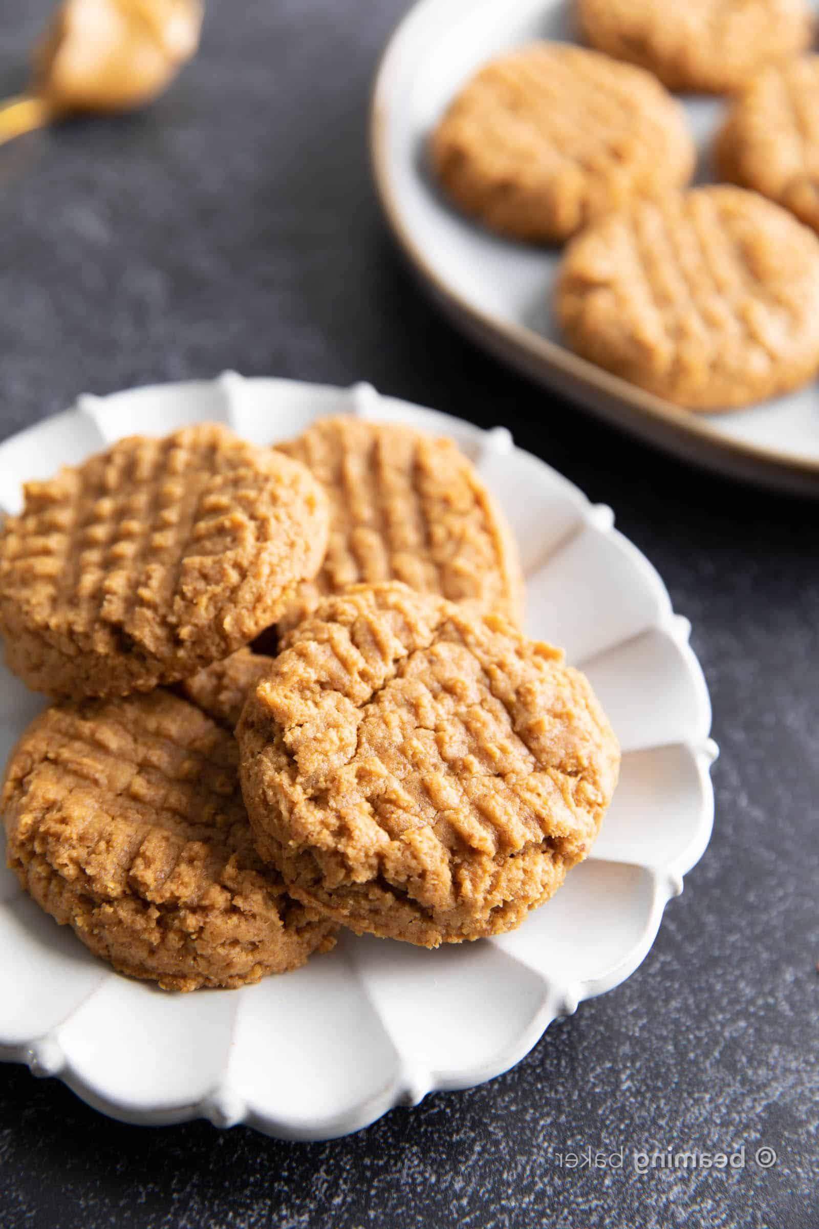 Gesunde Erdnussbutterkekse mit nur 4 Zutaten 5 Vier glutenfreie Erdnussbutter-Kekse gestapelt und auf einem weißen Teller verteilt.