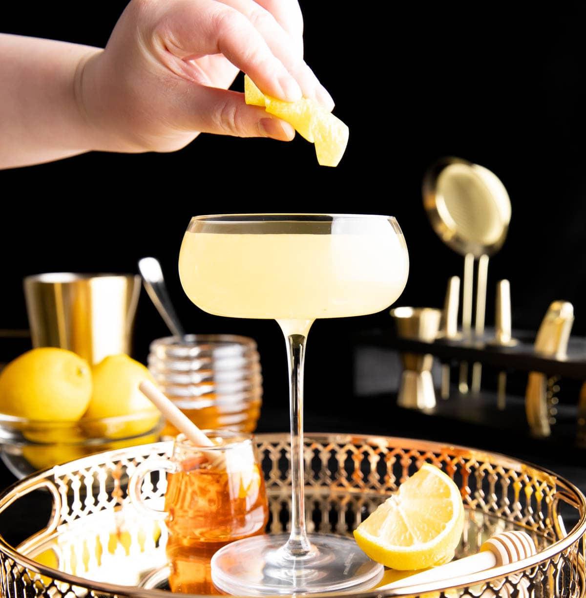 Bienenkniee-Cocktail 5 Ein Foto, das zeigt, wie man einen Bee’s Knees Cocktail zubereitet – Öle aus Zitronengarnitur ins Glas pressen