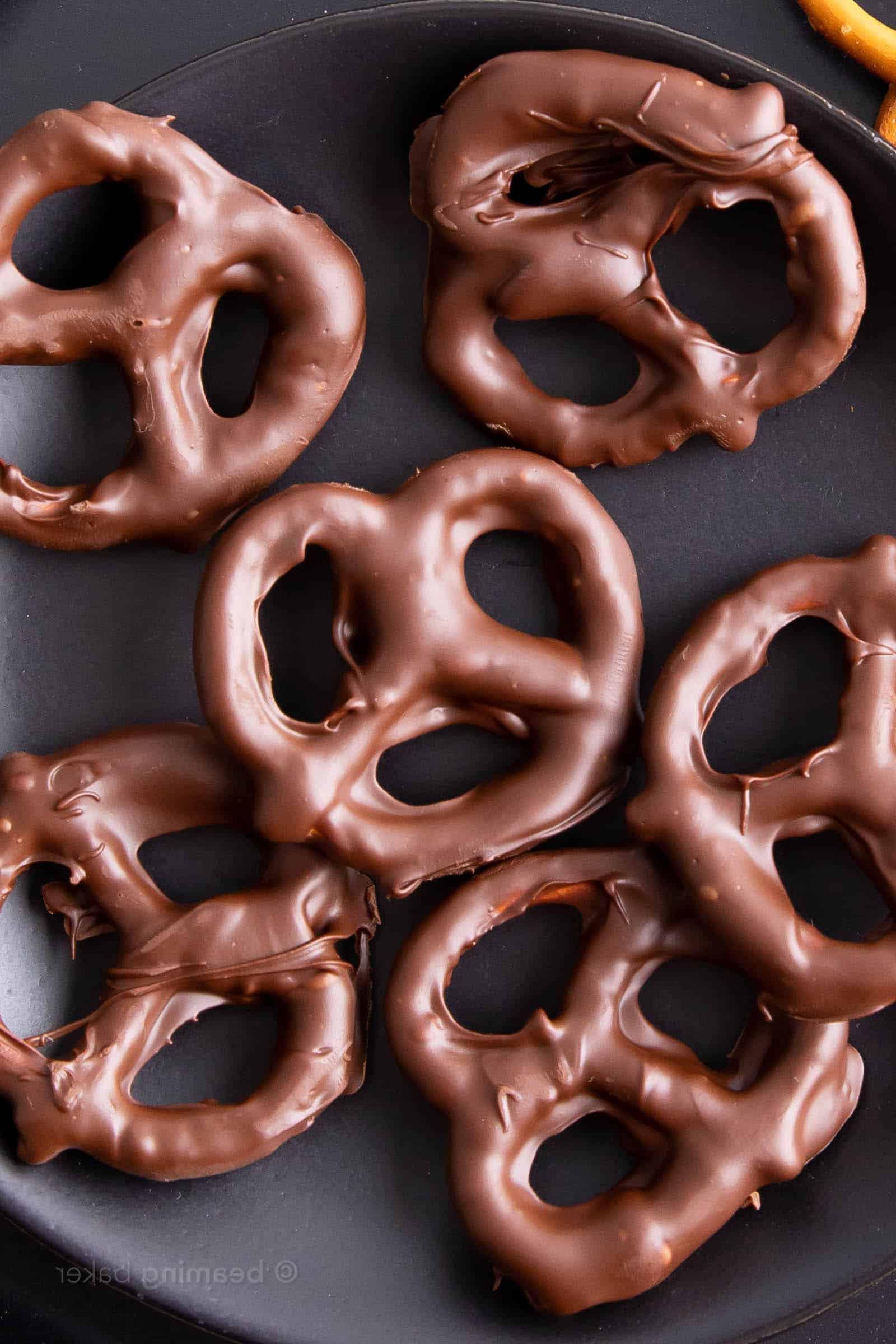 Nahaufnahme von veganen Schoko Brezeln auf einem schwarzen Teller mit einer unbedeckten Brezel im Vordergrund
