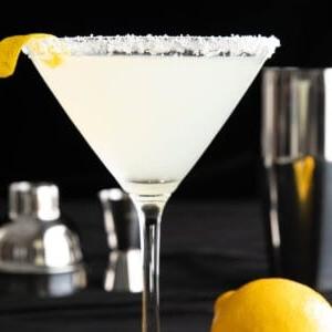 Das beste Lemon Drop Martini Rezept 7 Nahaufnahme eines Lemon Drop Martini mit Zitronen-Zucker-Rand und Zitronengarnitur auf schwarzem Hintergrund.