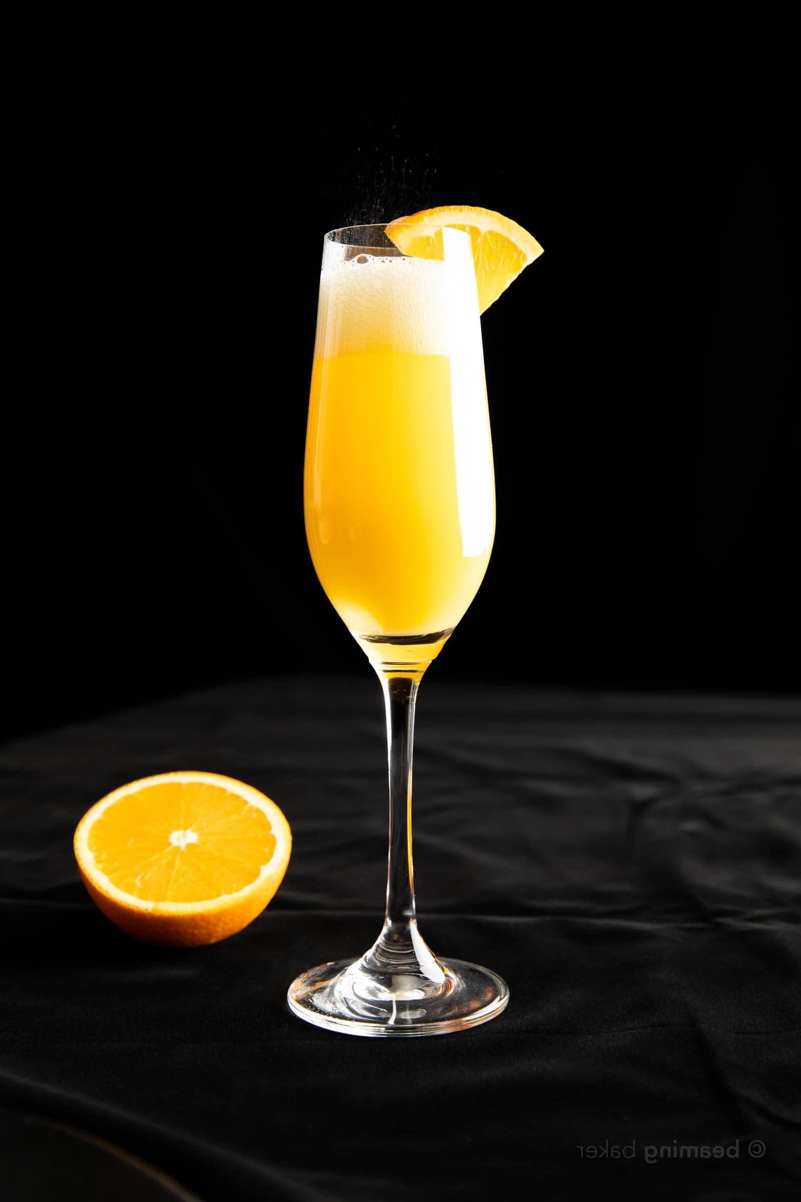 Ganzaufnahme eines Mimosa in einem Sektglas mit einer halben Orange