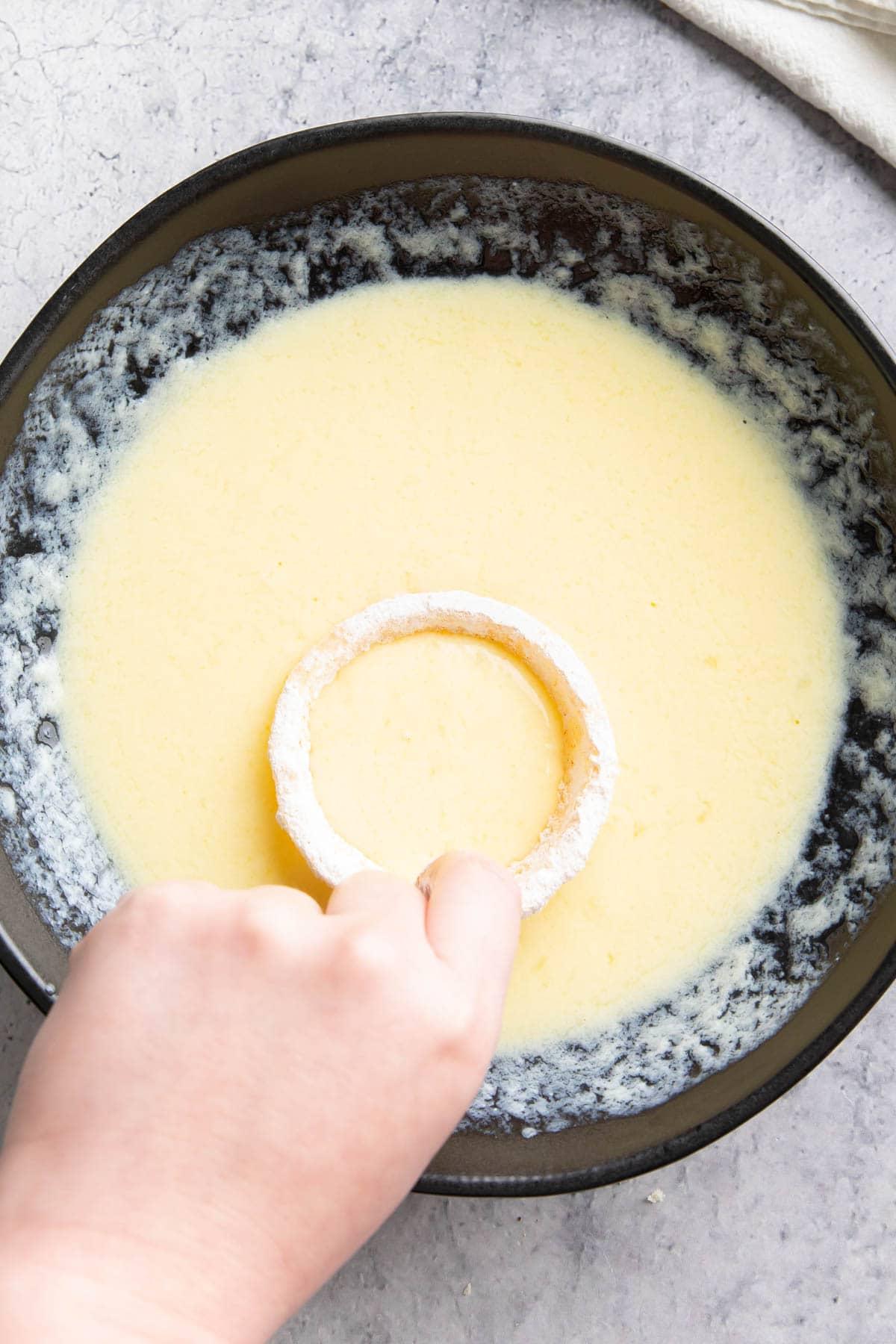 **Selbstgemachte Heißluftfritteusen-Zwiebelringe** 7 Einen Zwiebelring in die Eierbutter tauchen