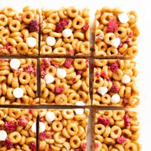 Müsliriegel Rezept – Gesund & Einfach! 9 Müsliriegel aus Cheerios, Obst und Schokoladenstückchen, geschnitten und servierfertig auf einem weißen Serviertablett.