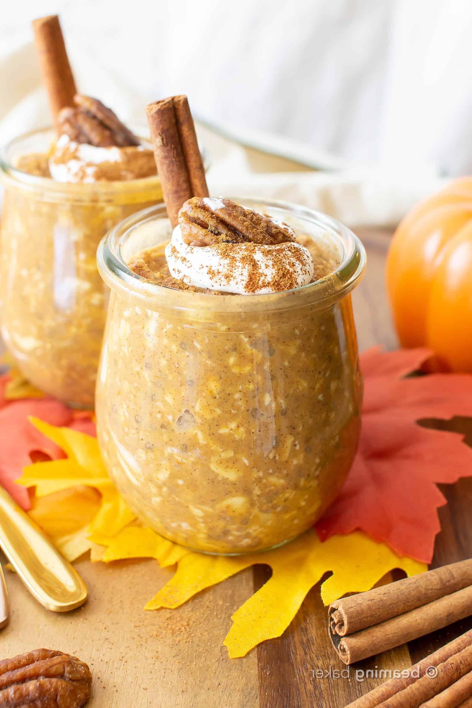 Gläser mit Kürbis Overnight Oats mit Schlagsahne und einer Zimtstange