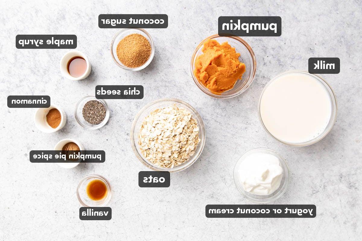 Zutaten für Kürbis Overnight Oats in kleinen Schüsseln abgemessen, darunter Haferflocken, Milch, Kürbispüree, Chiasamen, Gewürze, Joghurt und mehr