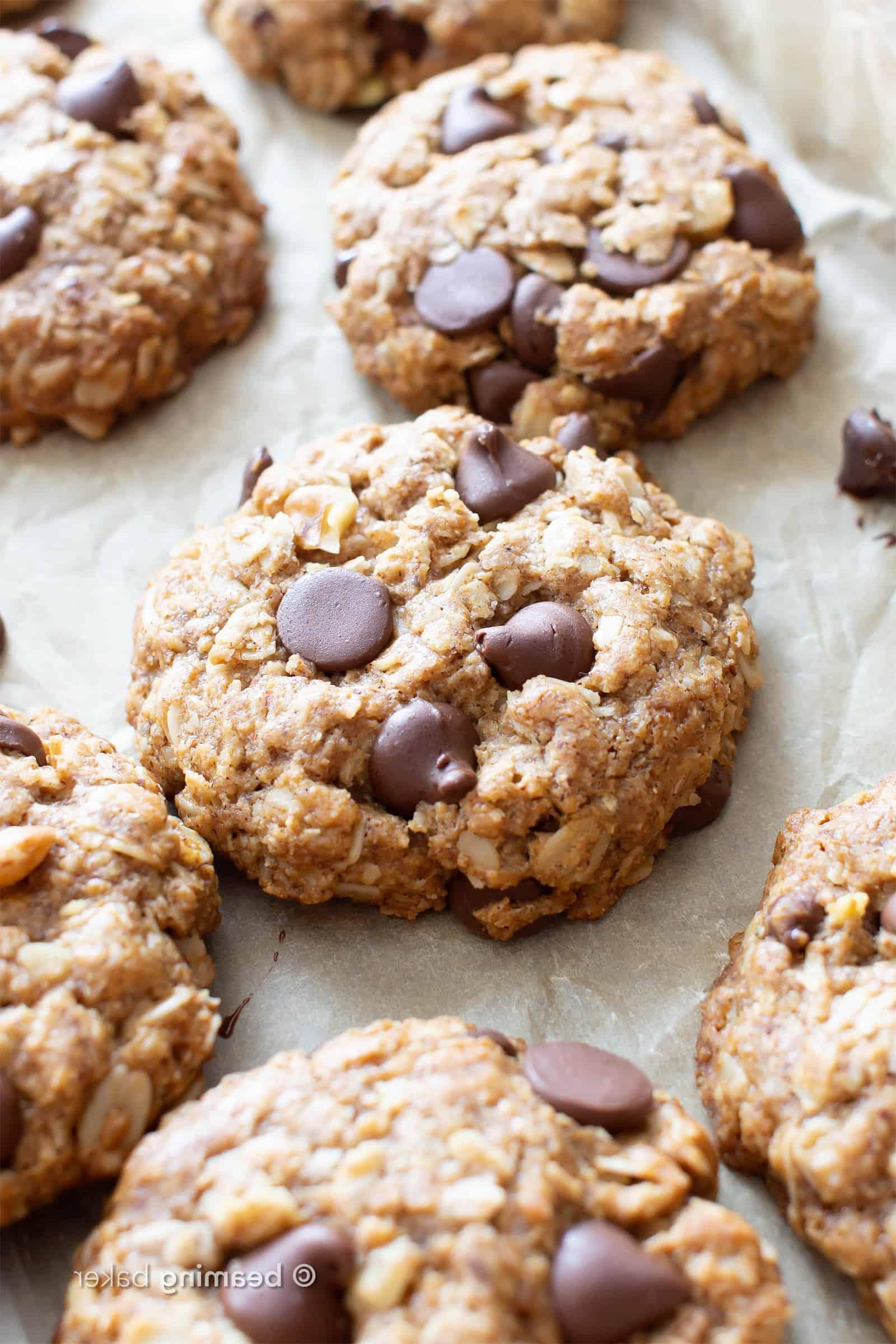Meine Lieblings vegane Haferflocken-Schoko-Chip-Cookies! 4 Milchfreie Haferkekse mit geschmolzenen Schokostückchen und Keksen im Hintergrund