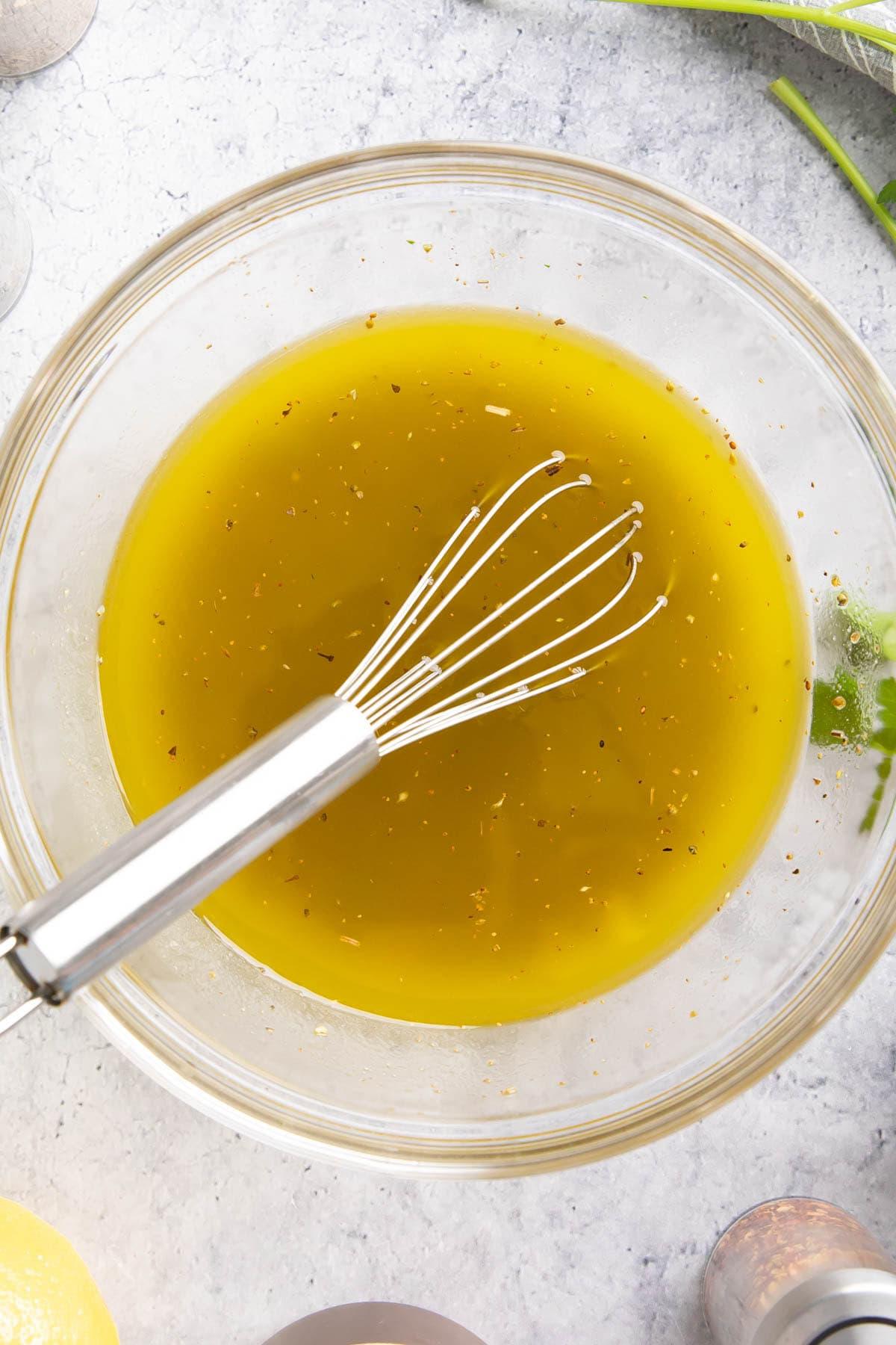 Italienisches Dressing Rezept {Einfach!} 4 Ein Schneebesen in einer Schüssel mit dieser Salatsauce, gefüllt mit Öl, Weißweinessig, Zitronensaft und Kräutern