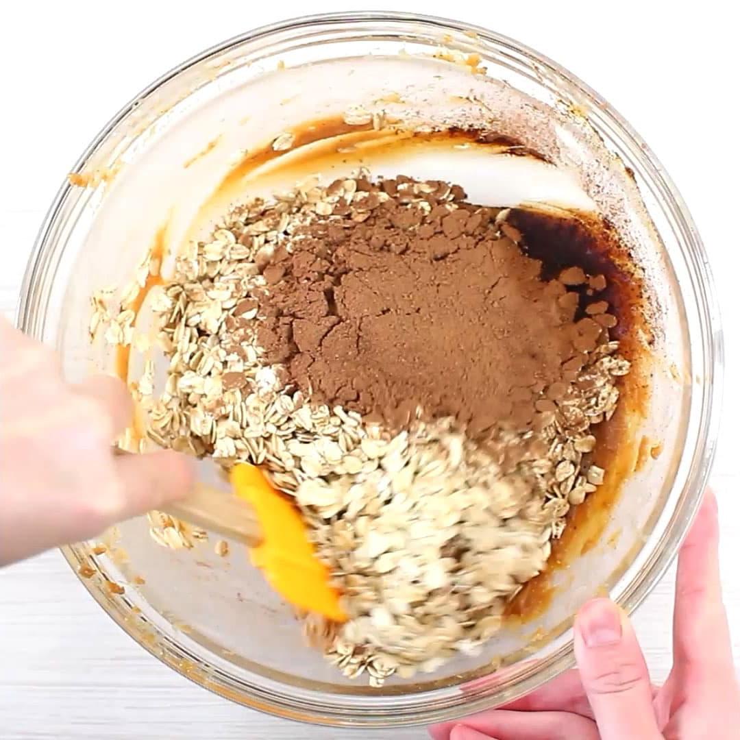 Eine Hand rührt und vermengt die gesunde No Bake Keks-Mischung in einer Rührschüssel.