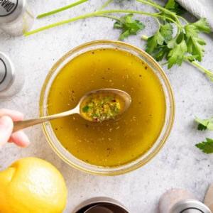 Italienisches Dressing Rezept {Einfach!} 6 Ein Löffel schöpft dieses italienische Dressing-Rezept aus einer Rührschüssel, um die Zutaten, einschließlich Kräuter, Olivenöl, Zitronensaft und mehr, zu präsentieren.