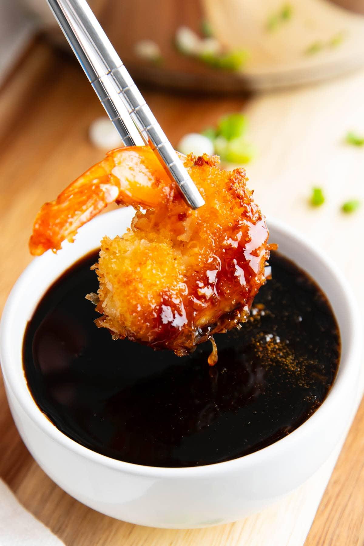 Aalsaucen-Rezept (Unagi-Sauce) 6 Essstäbchen halten eine in dieses Aalsoßenrezept getauchte Tempura-Garnele.