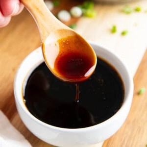 Aalsaucen-Rezept (Unagi-Sauce) 7 Jemand löffelt diese dicke Aalsoße in eine Dippschale.