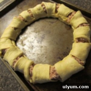 Tuna crescent ring with the dough carefully folded over the filling and sealed, ready for baking.