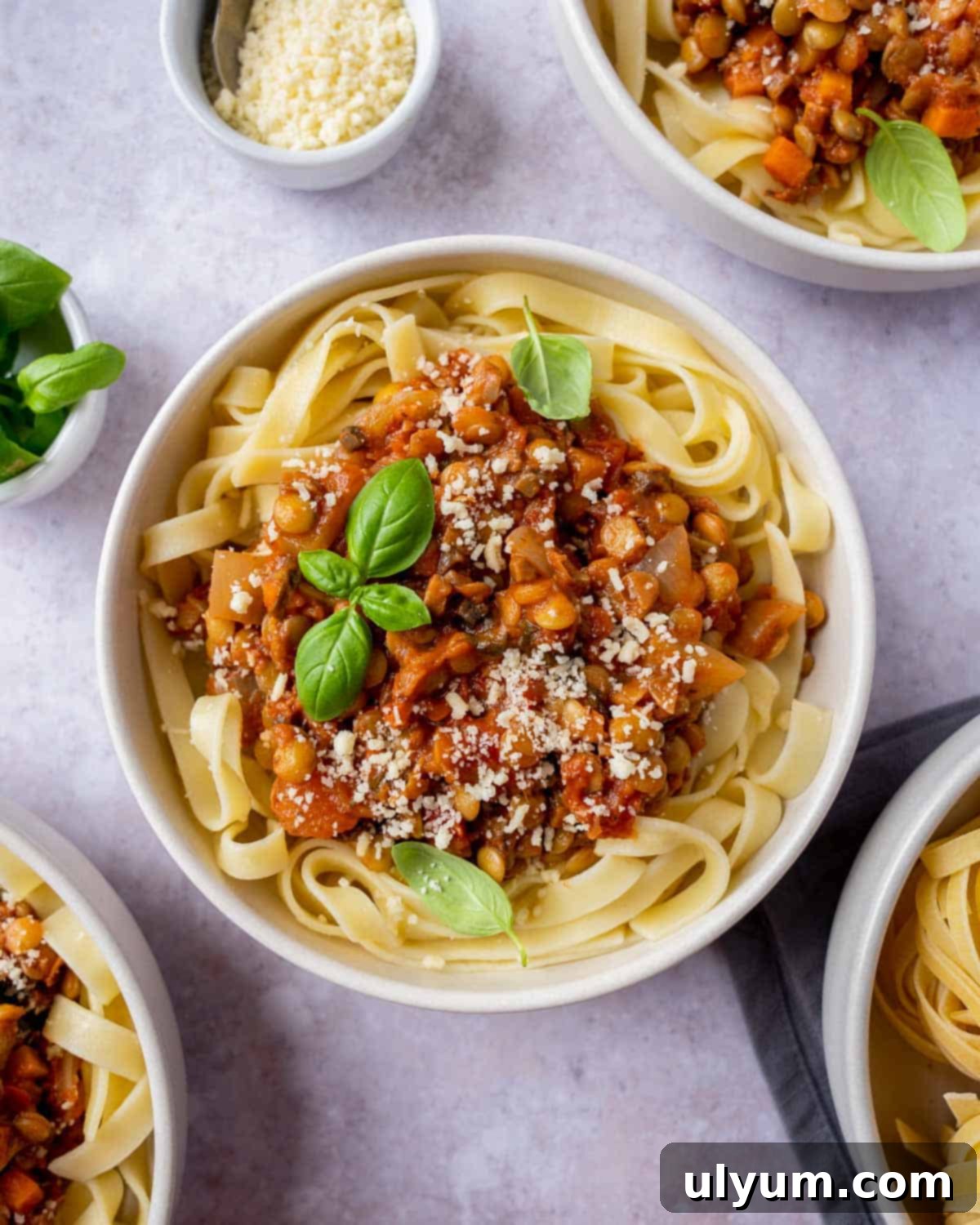 A hearty bowl of vegan mushroom lentil bolognese, garnished with fresh basil, served over pasta.