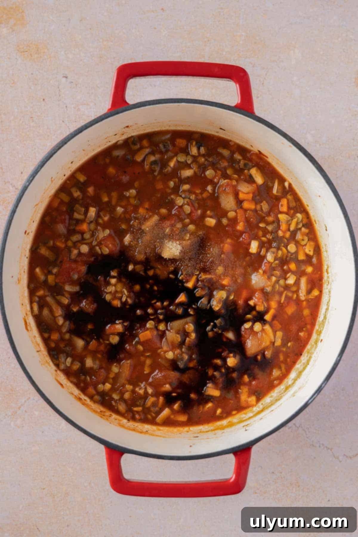 Adding vegan Worcestershire sauce to the simmering bolognese.