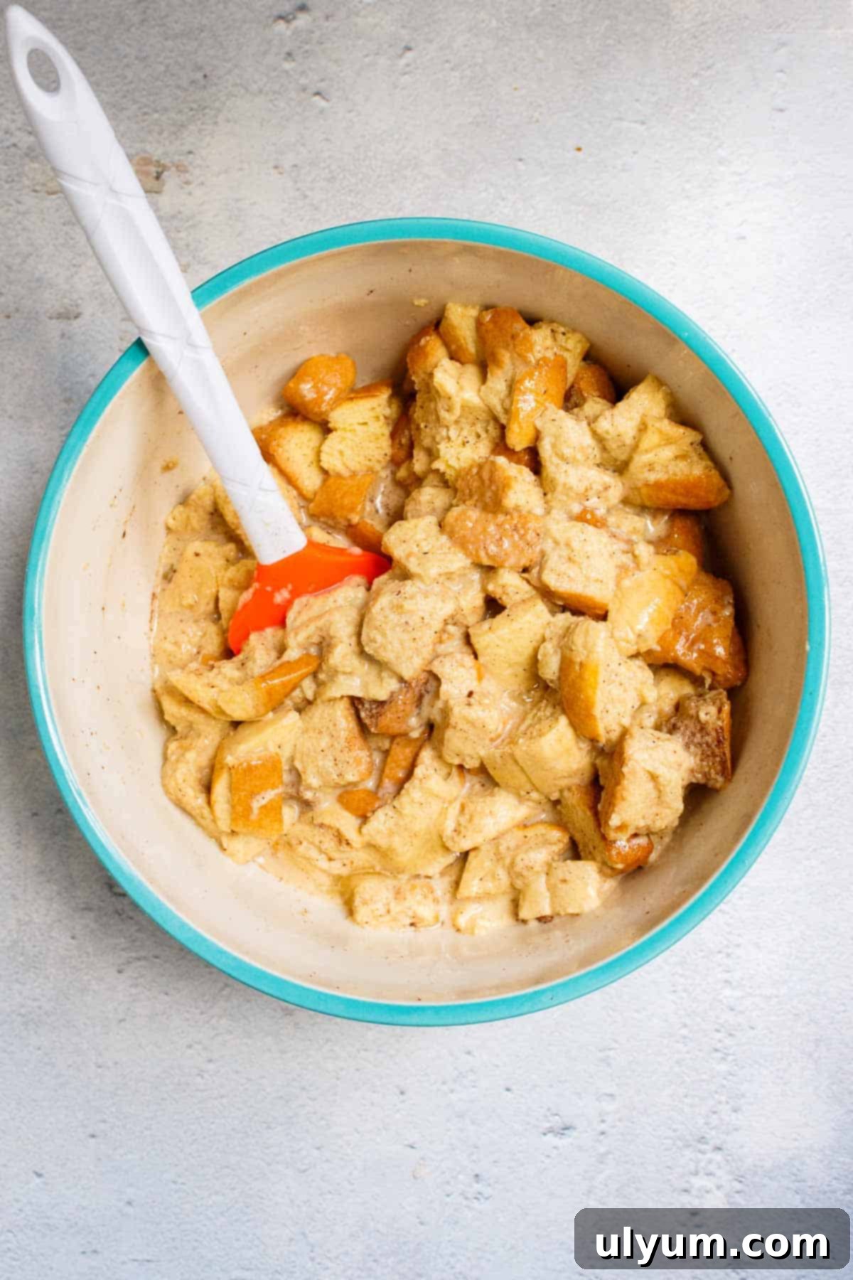 Brioche bread cubes coated in custard in mixing bowl.