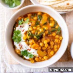 Vibrant Coconut Chickpea & Spinach Curry 14 Chickpea and spinach curry garnished with fresh cilantro and yogurt, served in a rustic bowl.