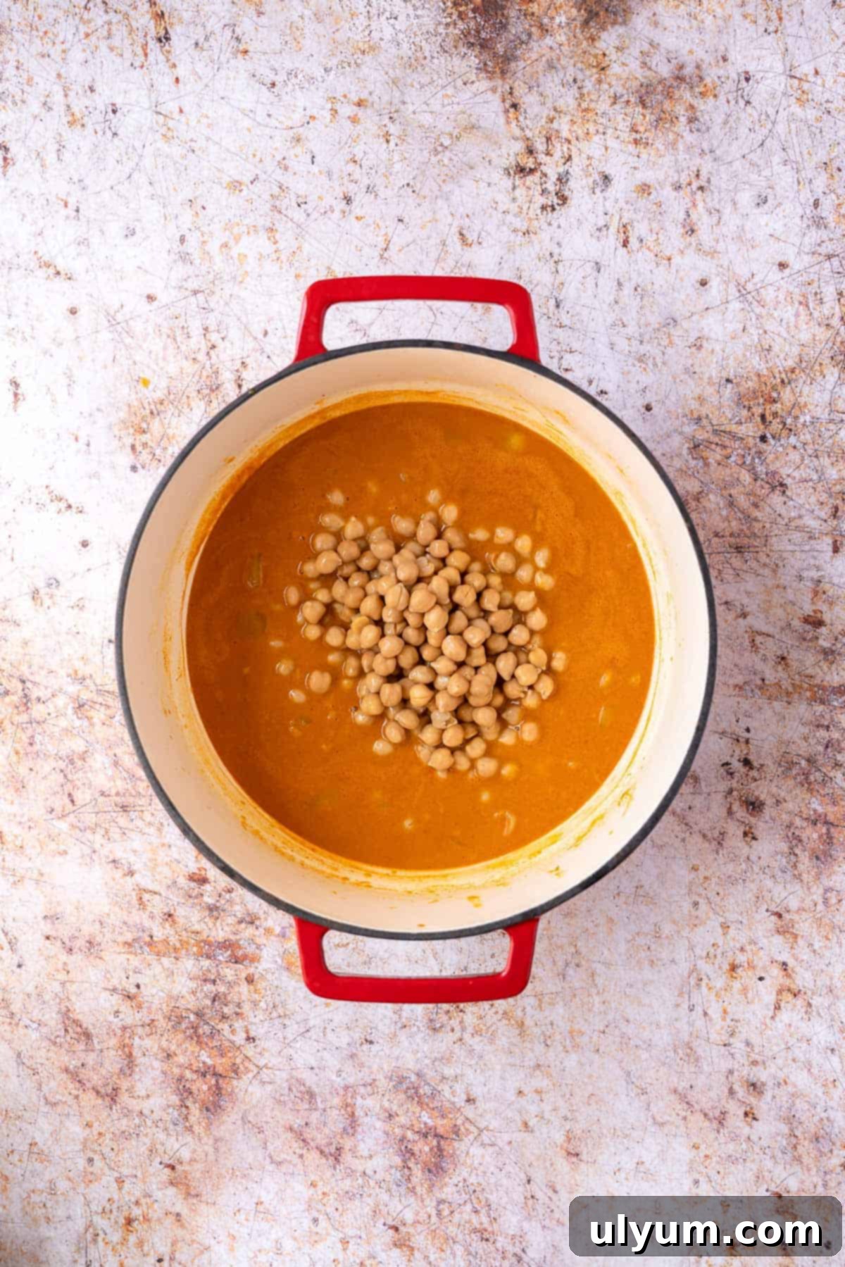 Vibrant Coconut Chickpea & Spinach Curry 8 Drained and rinsed canned chickpeas being added to the simmering curry sauce in a pot.