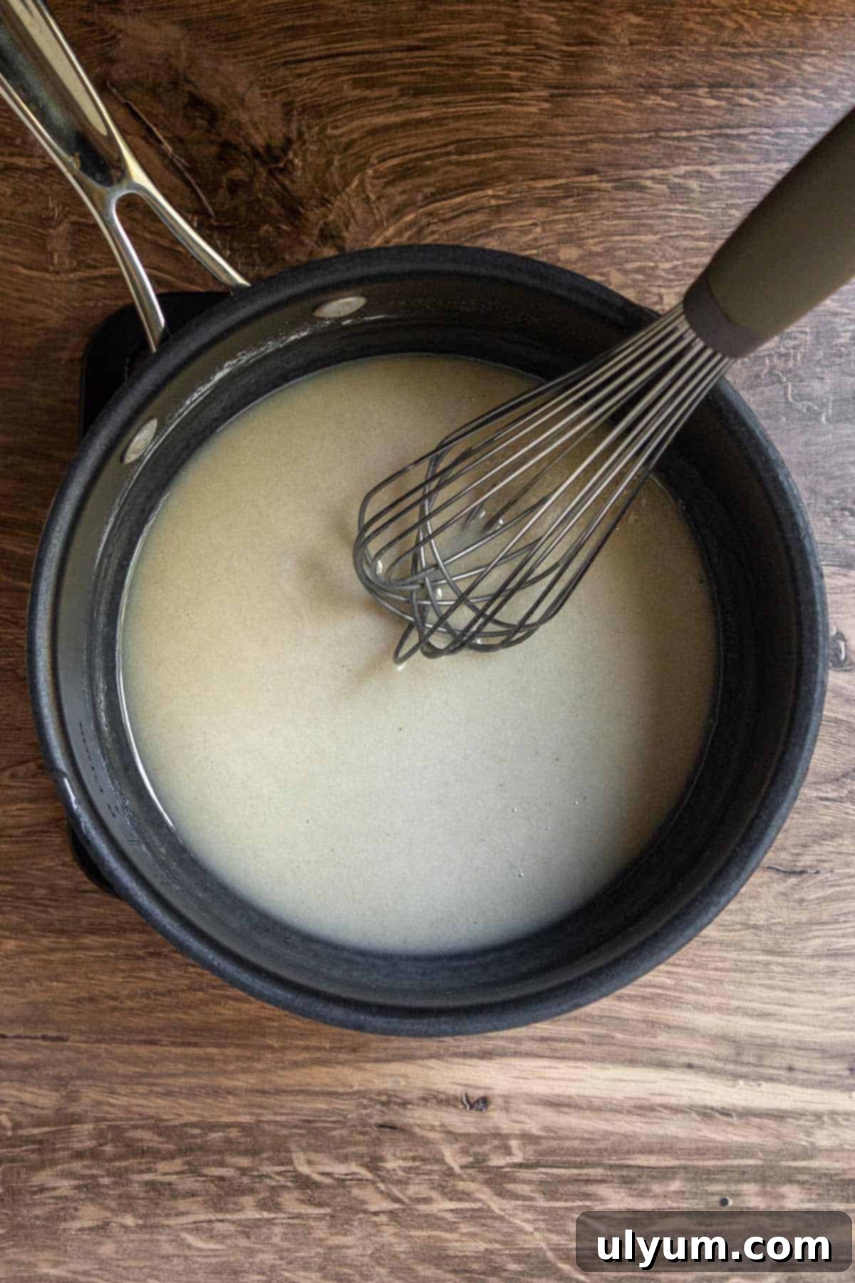 Flour being whisked into hot bacon grease until smooth
