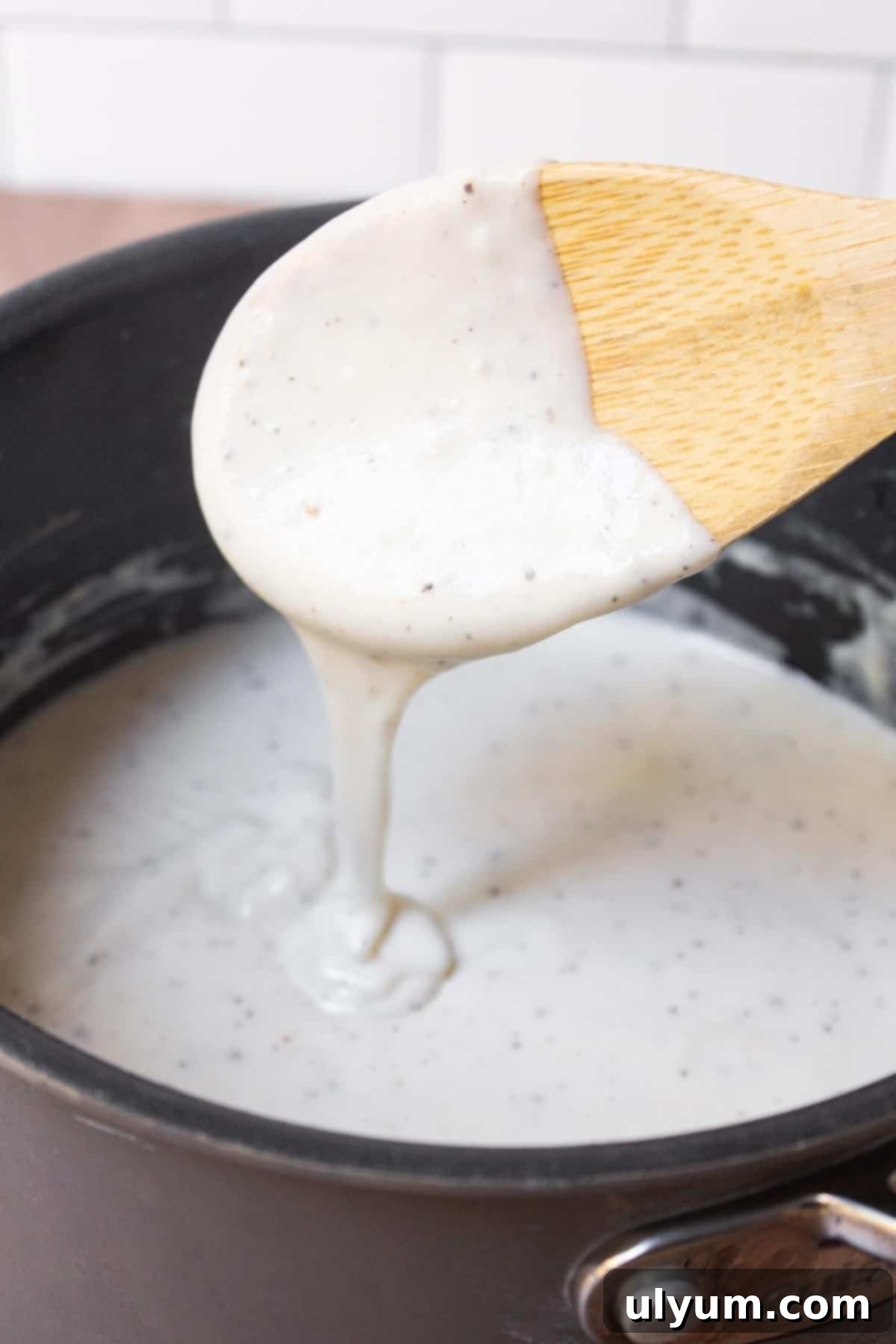 Thick southern country gravy dripping from a wooden spoon