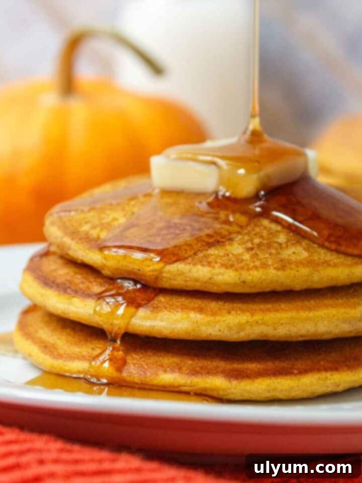 Bisquick Pumpkin Pancakes stacked with syrup and fall spices.