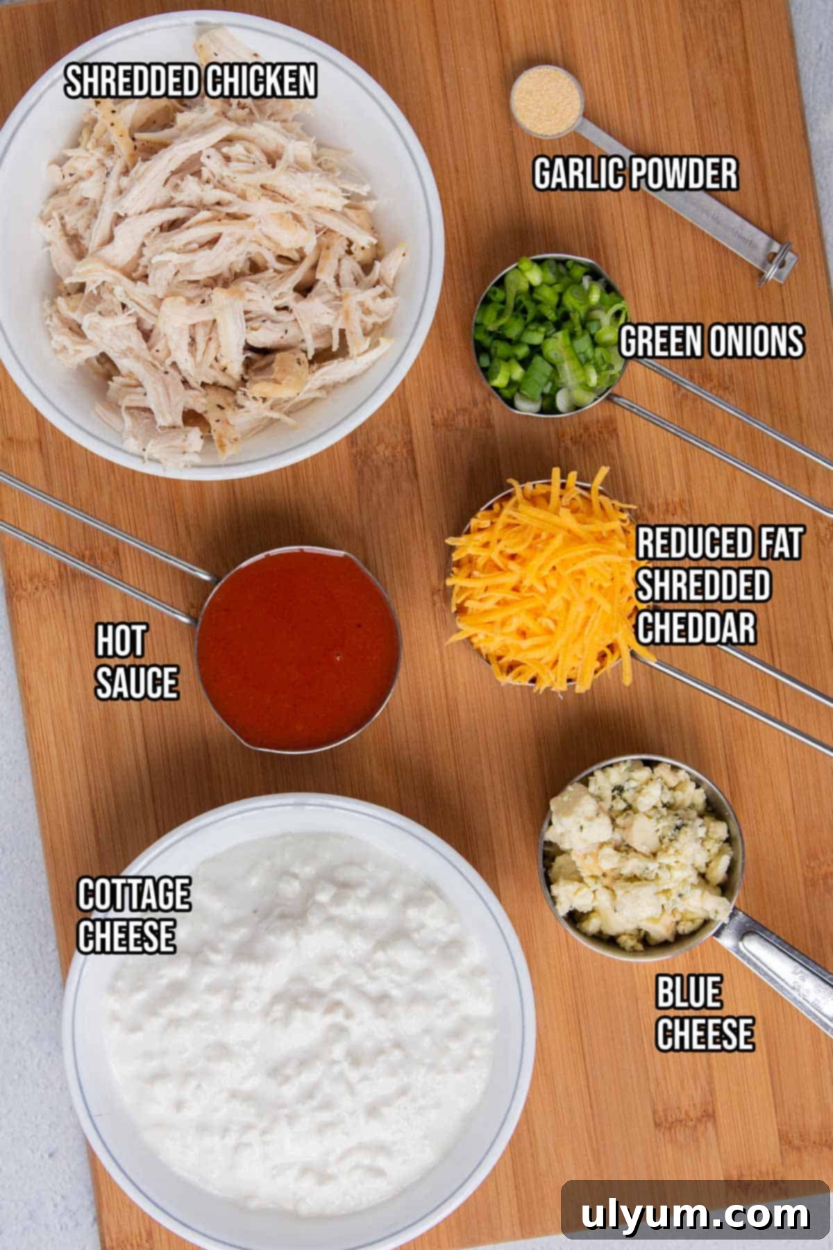 Lightened Buffalo Chicken Dip with Cottage Cheese 3 Healthy buffalo chicken dip ingredients laid out on a wooden board.
