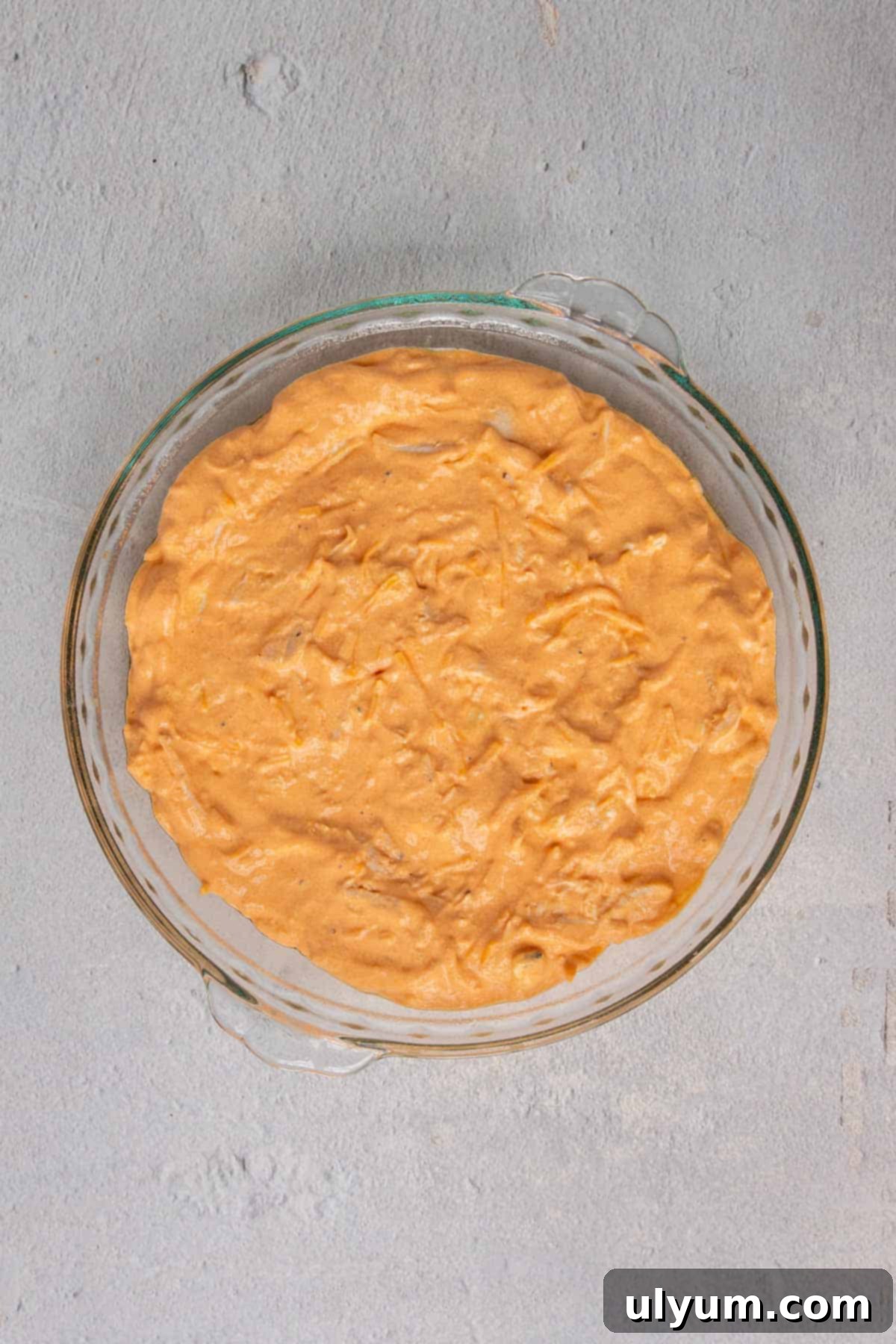 Unbaked buffalo chicken dip mixture in a pie dish, ready for the oven.