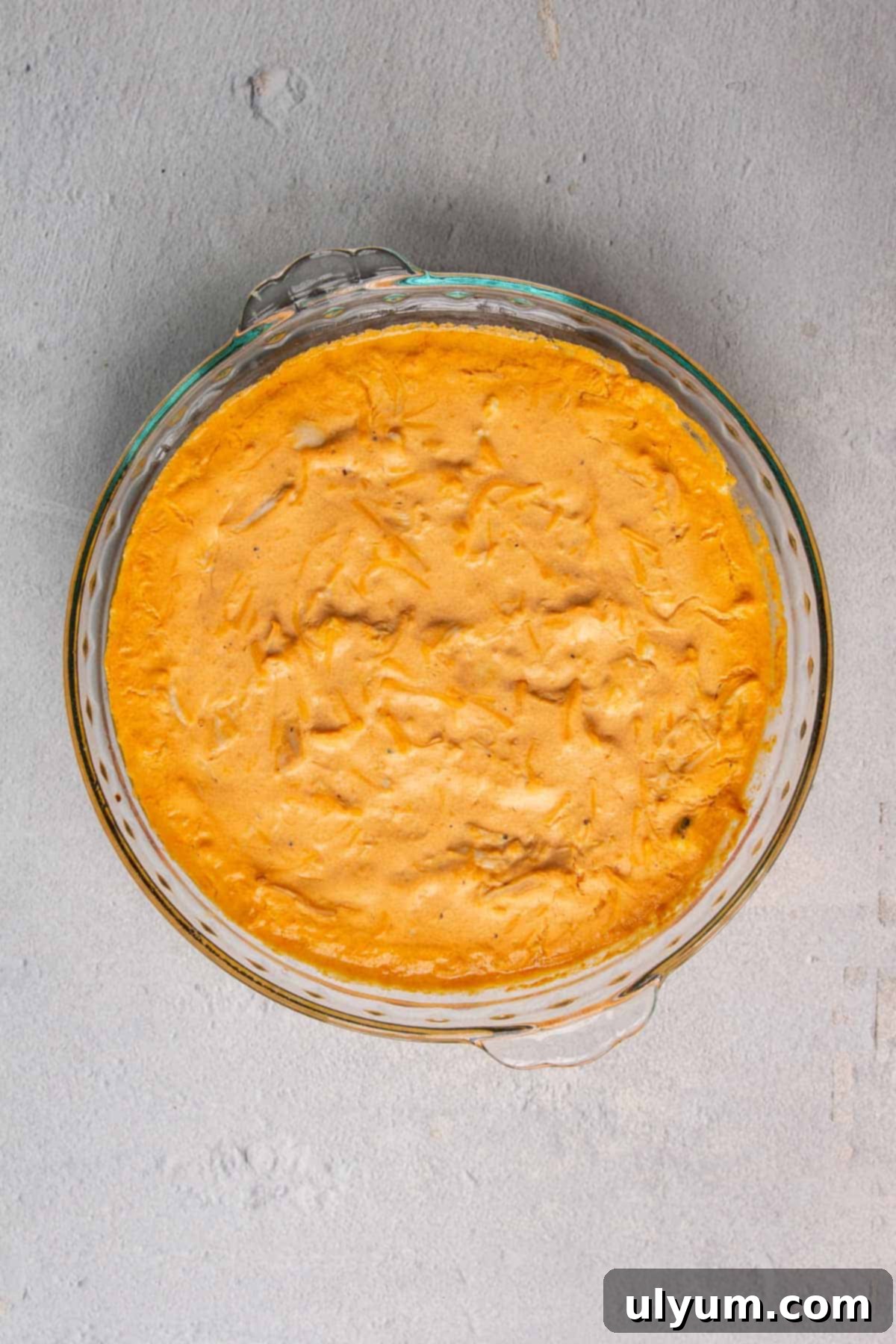 Baked healthy buffalo chicken dip in a pie plate, hot and bubbly from the oven.
