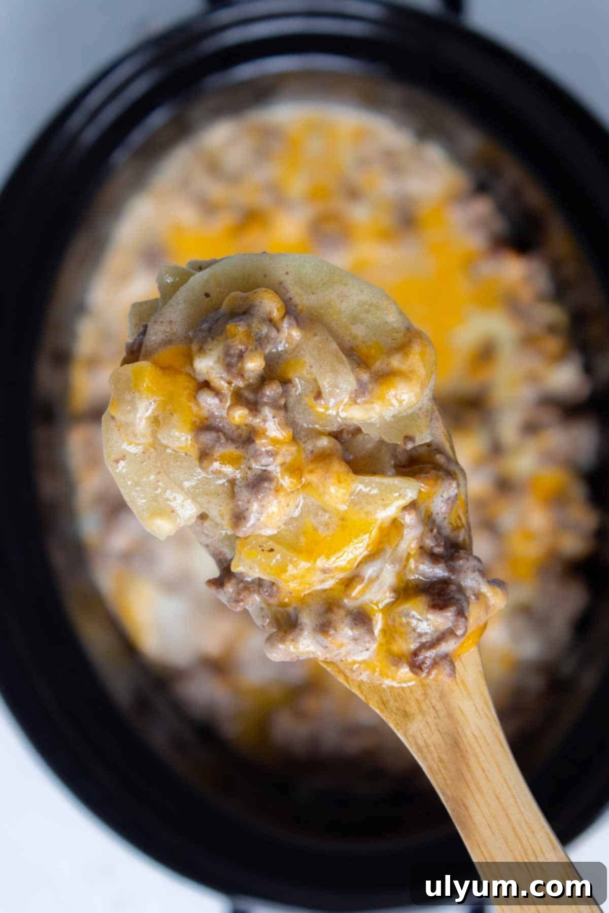 A spoonful of Crockpot Hamburger Potato Casserole, showcasing the melted cheese, tender potatoes, and ground beef mixture.