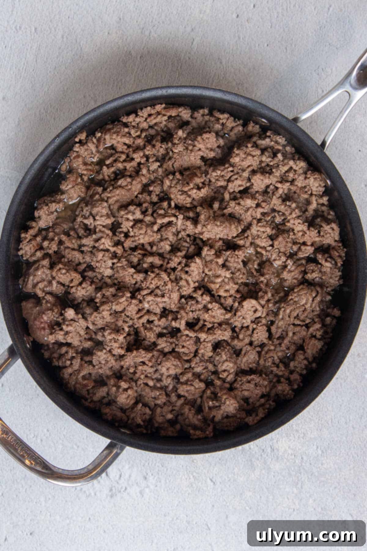 Ground beef browning in a large skillet over medium-high heat, showing the meat changing color as it cooks.
