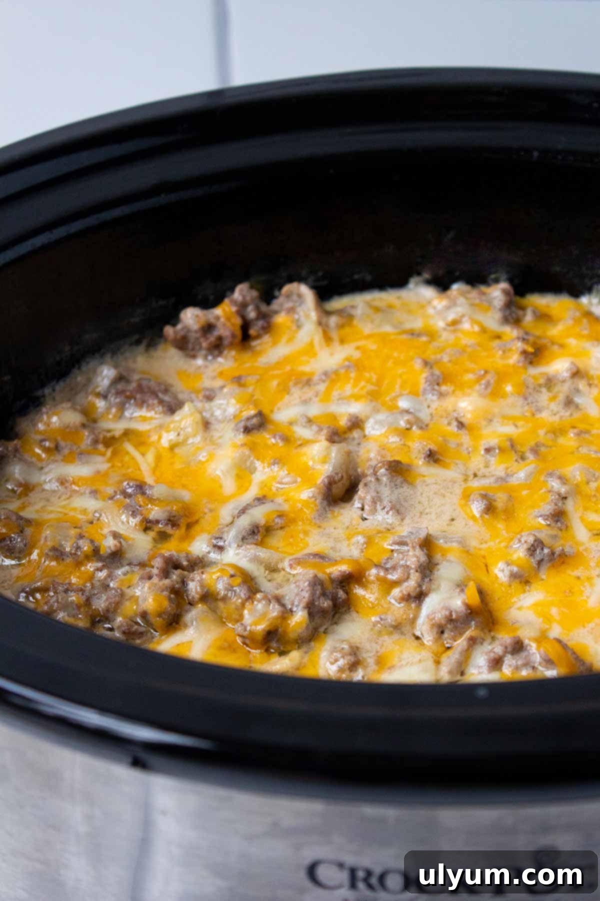The Crockpot Hamburger Potato Casserole cooked and ready to serve, steaming hot in the slow cooker with melted cheese on top.