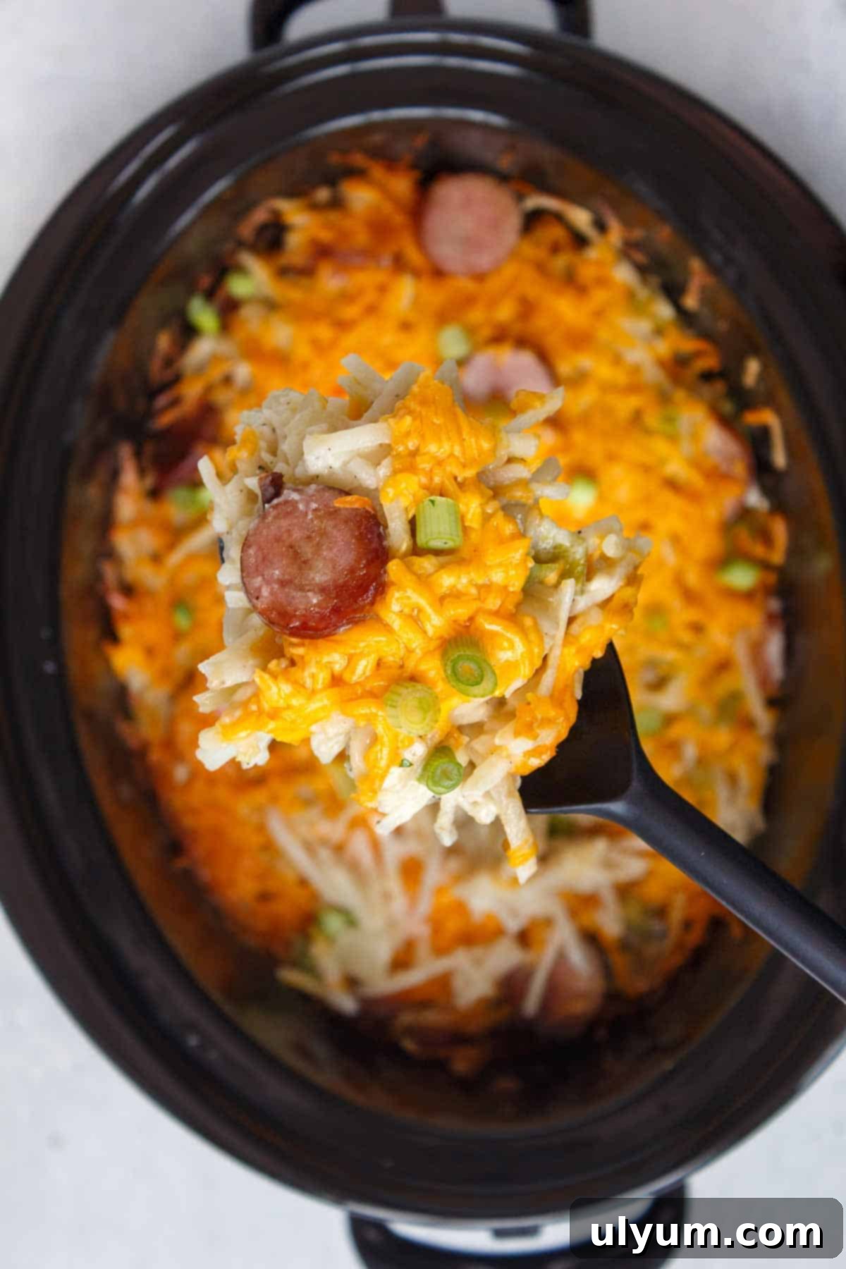Slow Cooker Cheesy Kielbasa Hash Brown Casserole on a serving spoon
