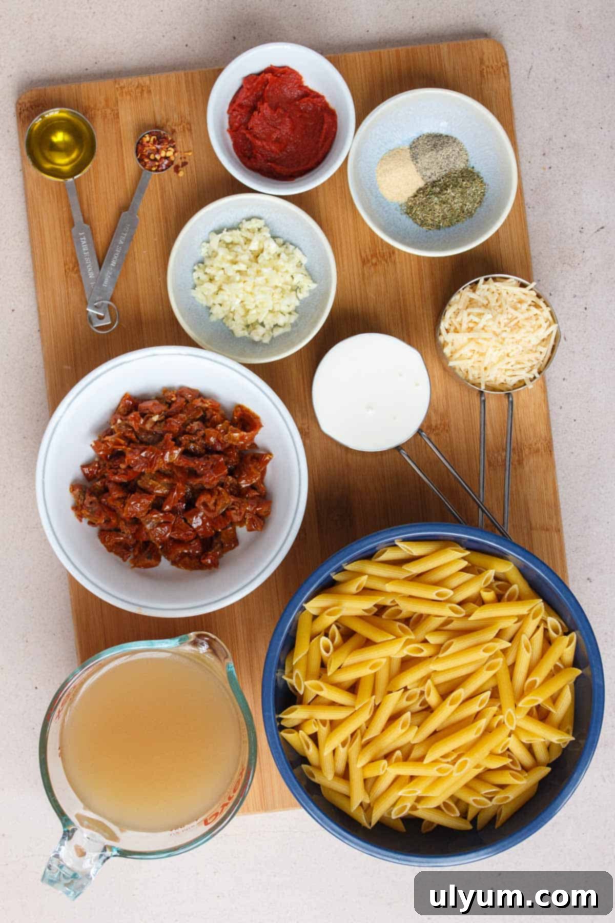 Effortless One-Pot Sun-Dried Tomato Pasta 3 A collection of fresh ingredients for One Pot Sun-Dried Tomato Pasta including penne, sun-dried tomatoes, garlic, and cream