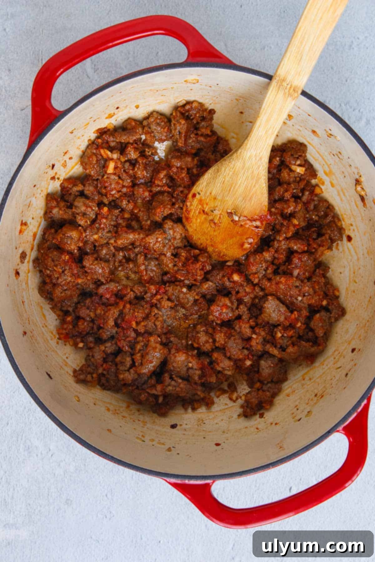 Creamy One-Pot Italian Sausage Pasta 7 Tomato paste being stirred into cooked Italian sausage, forming a rich base.