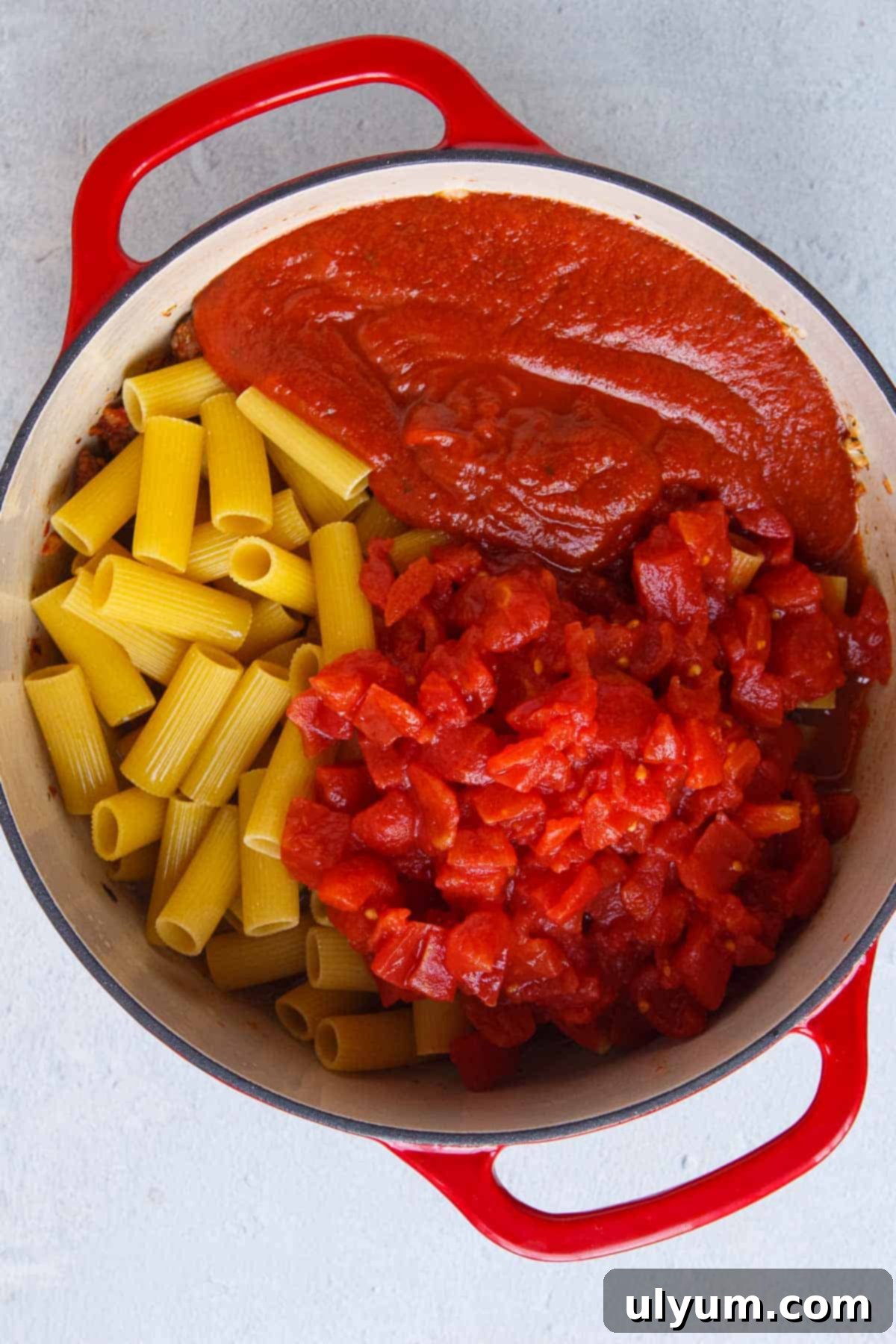Creamy One-Pot Italian Sausage Pasta 8 Uncooked rigatoni, diced tomatoes, marinara sauce, and chicken broth added to a large pot, ready to simmer.