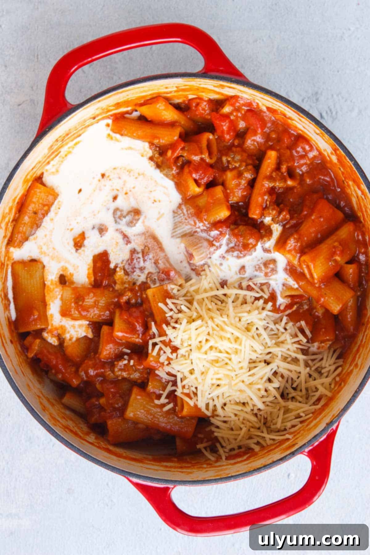 Creamy One-Pot Italian Sausage Pasta 10 Heavy cream and Parmesan cheese being stirred into the cooked rigatoni pasta.